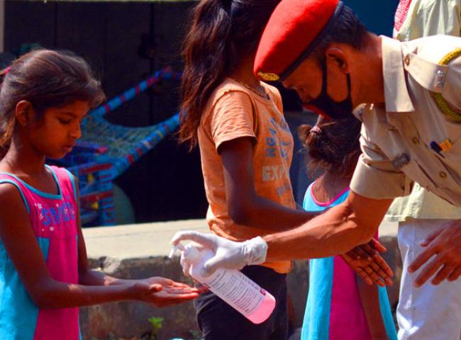 A policeman giving hand sanitizer to a young girl at road side in Guwahati